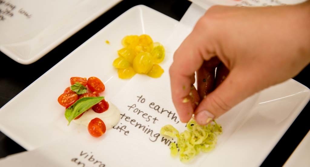 person placing tiny tomato slices on a plate